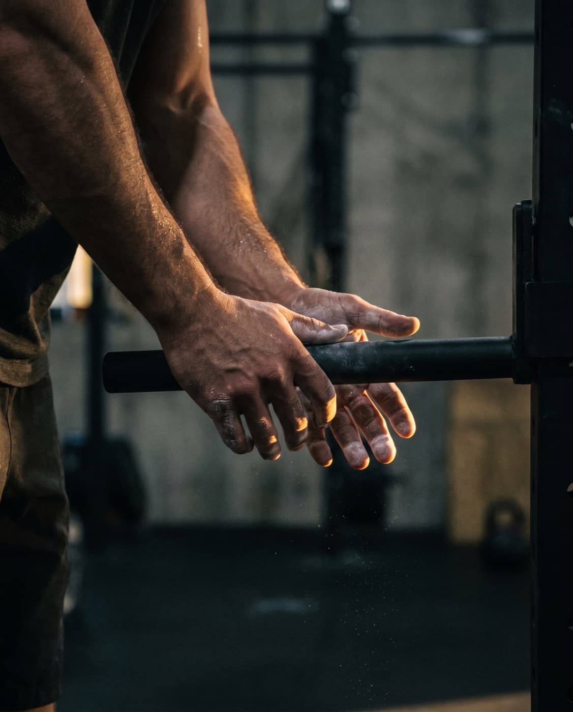 Chalked hands gripping a barbell before a lift